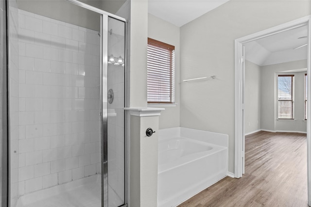 full bathroom featuring lofted ceiling, a garden tub, wood finished floors, baseboards, and a shower stall