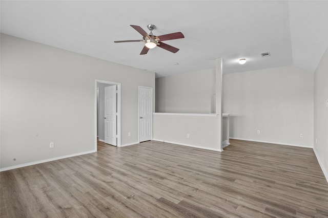 unfurnished room with a ceiling fan, visible vents, vaulted ceiling, and light wood-style flooring