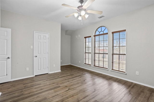 unfurnished room featuring ceiling fan, dark wood-style flooring, visible vents, and baseboards