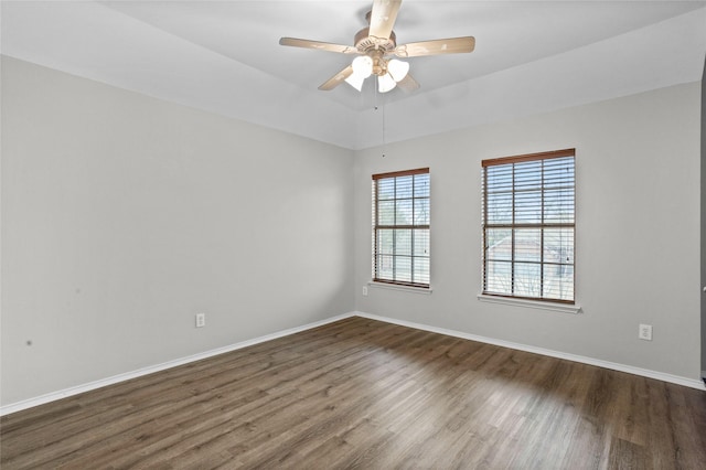 spare room featuring a ceiling fan, dark wood finished floors, and baseboards