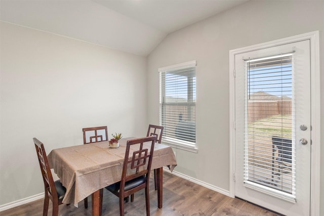 dining space featuring vaulted ceiling, baseboards, and wood finished floors