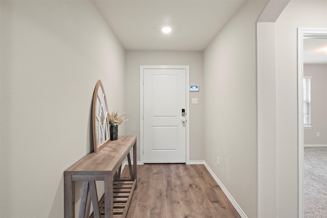 doorway featuring arched walkways, wood finished floors, and baseboards