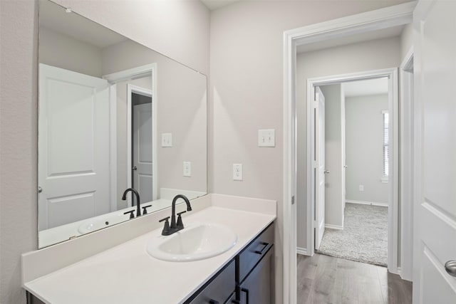 bathroom with baseboards, wood finished floors, and vanity