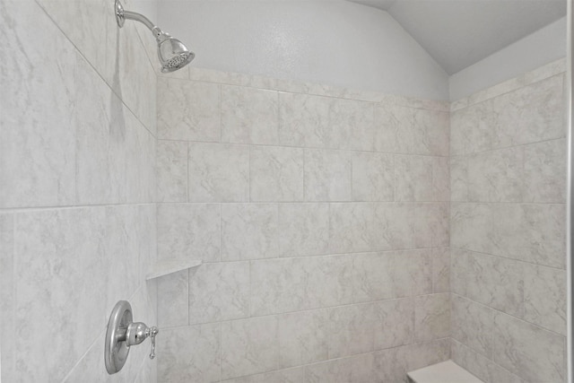 bathroom featuring vaulted ceiling and a tile shower