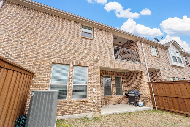 rear view of property featuring brick siding, a patio, a fenced backyard, and central AC unit