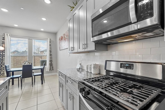 kitchen featuring appliances with stainless steel finishes, gray cabinets, light tile patterned floors, and light stone countertops