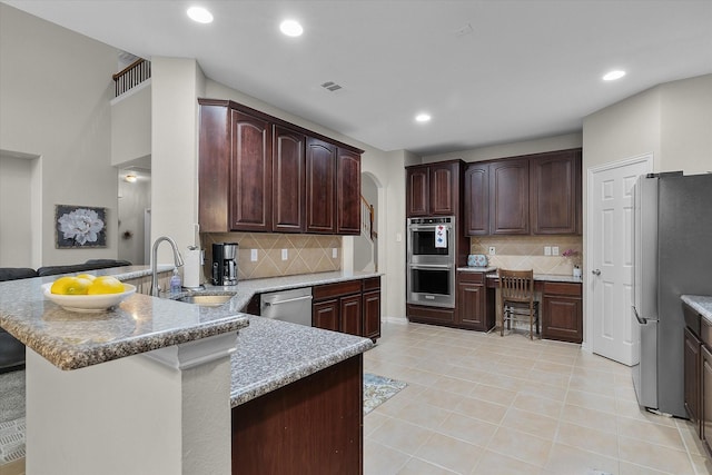 kitchen featuring recessed lighting, appliances with stainless steel finishes, light tile patterned flooring, a sink, and a peninsula