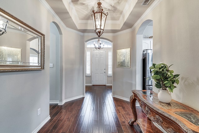 foyer with arched walkways, a notable chandelier, dark wood-style flooring, baseboards, and a tray ceiling