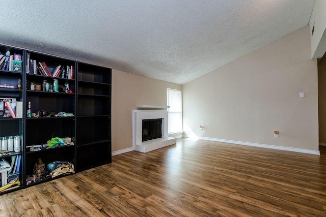 living room with baseboards, lofted ceiling, wood finished floors, a textured ceiling, and a fireplace