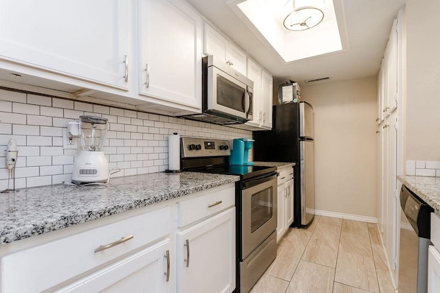 kitchen with light stone countertops, visible vents, appliances with stainless steel finishes, and white cabinets