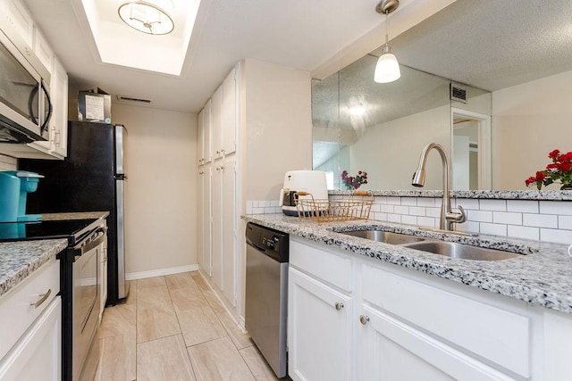 kitchen featuring visible vents, light stone counters, stainless steel appliances, white cabinetry, and a sink