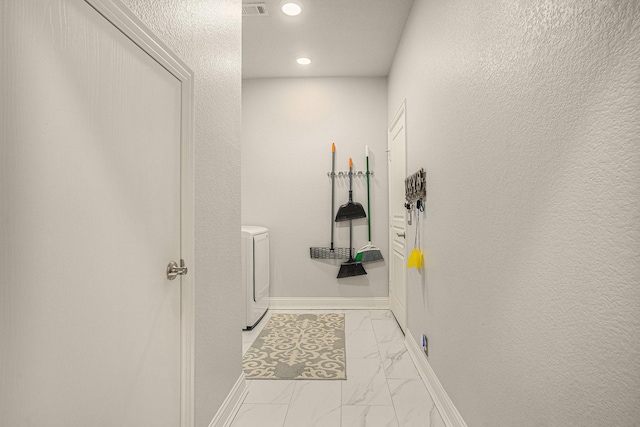 corridor with visible vents, baseboards, a textured wall, marble finish floor, and washer and dryer