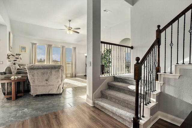 stairway featuring ceiling fan, wood finished floors, visible vents, and baseboards