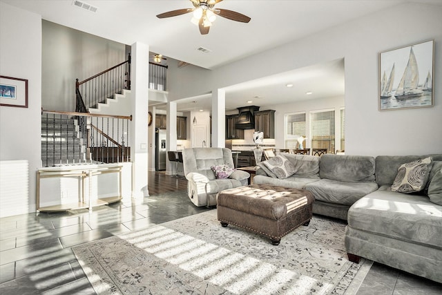 living area featuring a ceiling fan, visible vents, and stairway