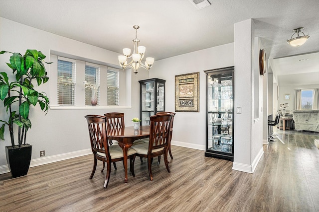 dining space with a chandelier, wood finished floors, visible vents, and baseboards