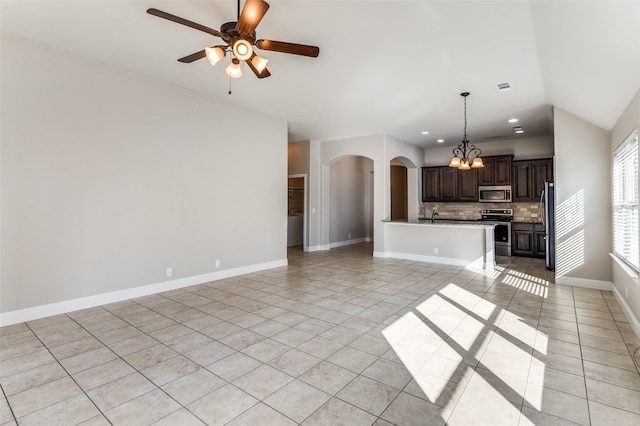 unfurnished living room featuring arched walkways, light tile patterned floors, lofted ceiling, baseboards, and ceiling fan with notable chandelier