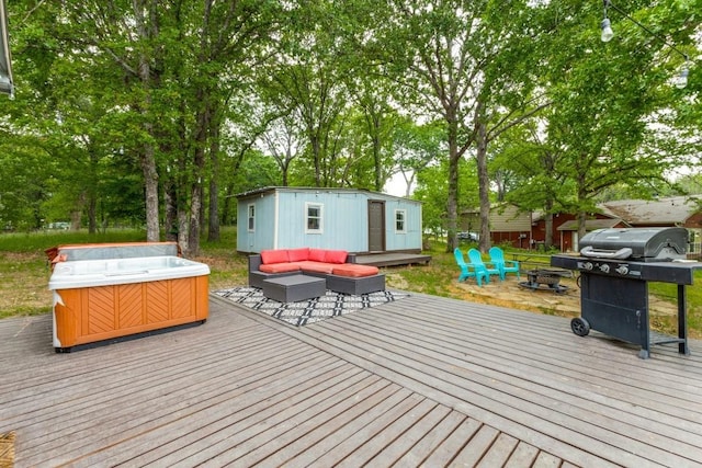 deck featuring area for grilling, an outdoor structure, an outdoor living space with a fire pit, and a hot tub