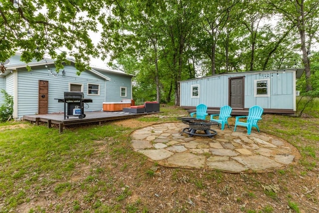 view of yard featuring an outbuilding, a hot tub, a patio area, a fire pit, and a wooden deck