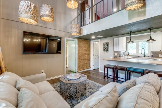 living area featuring a high ceiling, baseboards, and dark wood finished floors