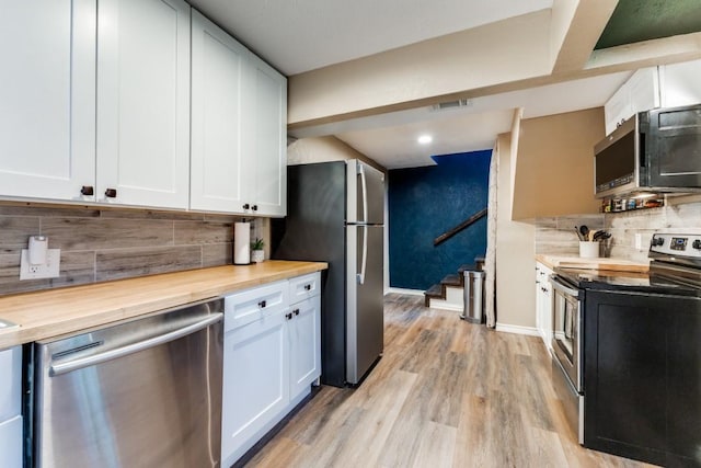 kitchen featuring stainless steel appliances, butcher block countertops, and white cabinets