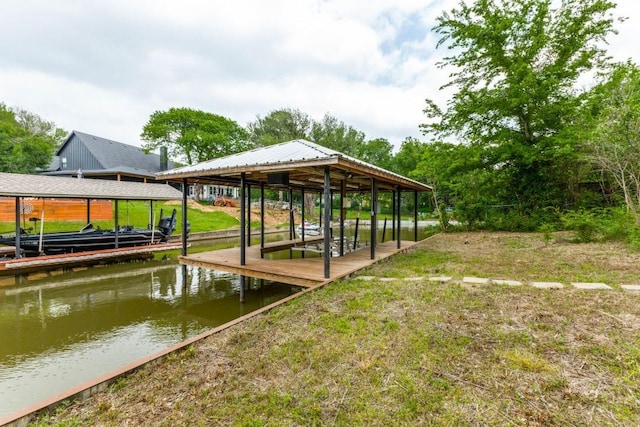 view of dock featuring a water view, a lawn, and boat lift