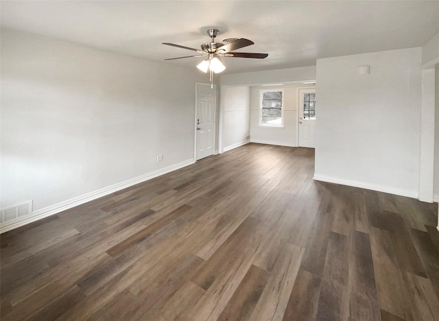 spare room with dark wood-type flooring, visible vents, baseboards, and a ceiling fan