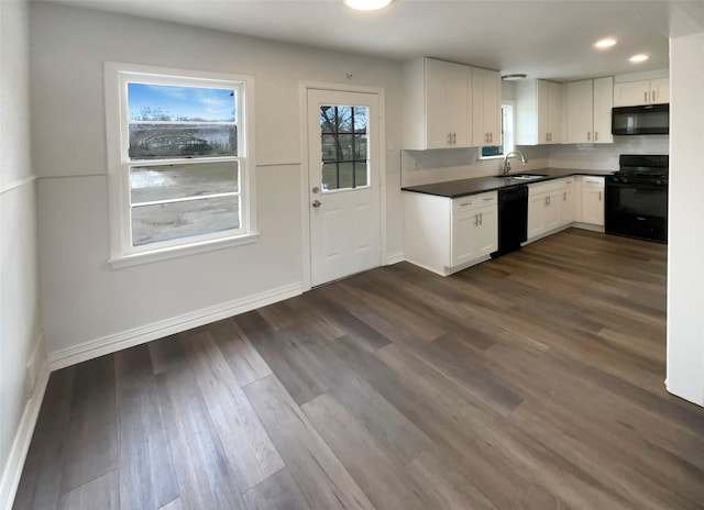 kitchen with dark countertops, white cabinetry, a sink, and black appliances