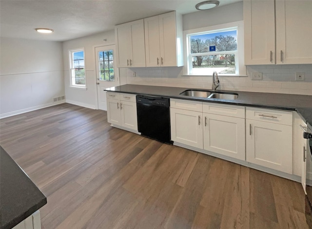 kitchen with dark countertops, black dishwasher, white cabinetry, and a sink