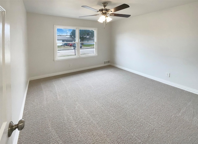 carpeted spare room featuring a ceiling fan, visible vents, and baseboards