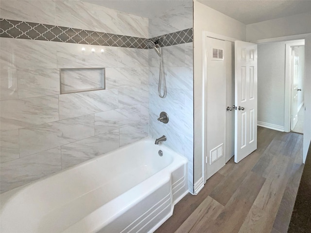 full bathroom featuring baseboards, visible vents, shower / tub combination, and wood finished floors