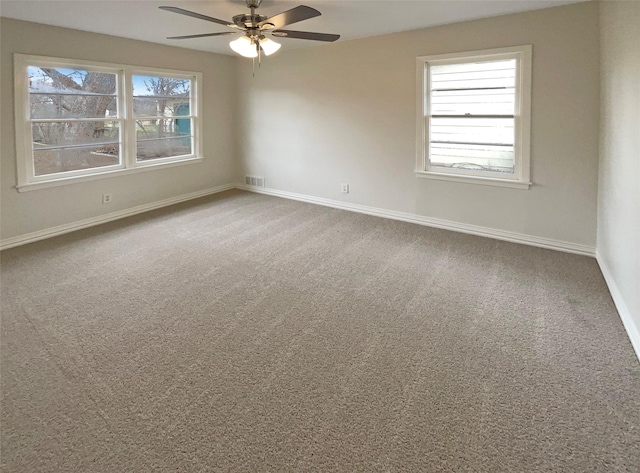 unfurnished room featuring visible vents, a wealth of natural light, and carpet flooring