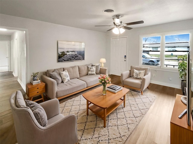 living area featuring a ceiling fan, baseboards, visible vents, and wood finished floors