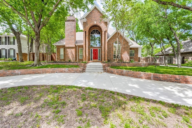 view of front of house featuring a chimney, fence, and brick siding