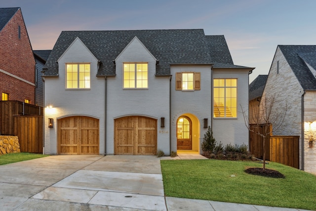 view of front of property with a garage, concrete driveway, fence, a front lawn, and brick siding