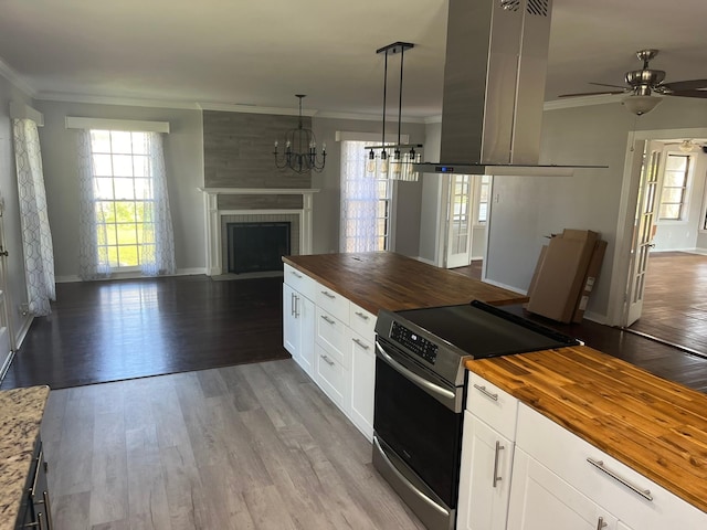 kitchen with stainless steel electric range oven, hanging light fixtures, open floor plan, and wood counters