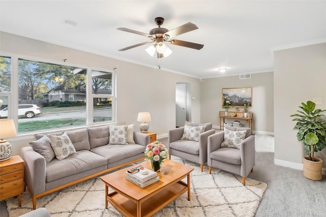 living area with crown molding, visible vents, a ceiling fan, light carpet, and baseboards