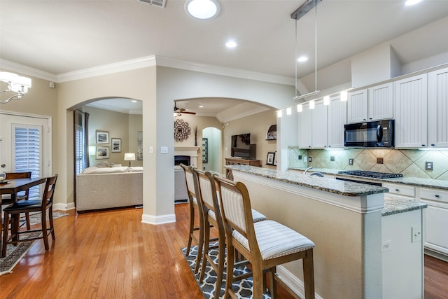 kitchen with black microwave, open floor plan, a kitchen island, and white cabinets