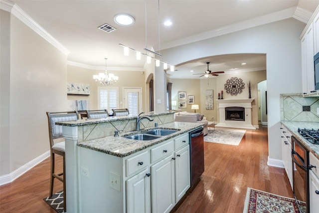 kitchen with a center island with sink, open floor plan, a kitchen bar, white cabinetry, and a sink