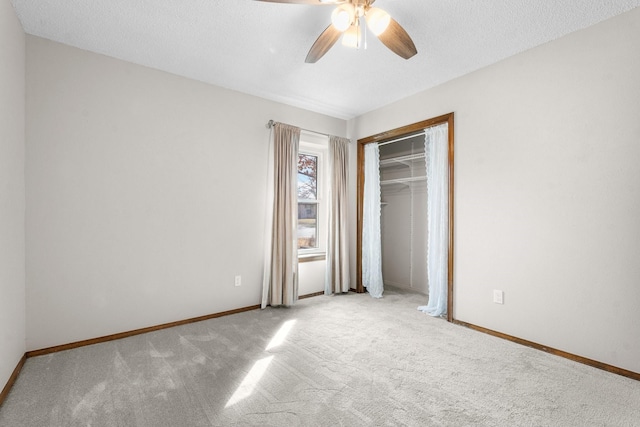 unfurnished bedroom featuring light colored carpet, a textured ceiling, and baseboards