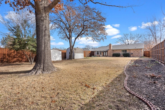 view of yard featuring a storage shed, a fenced backyard, and an outdoor structure