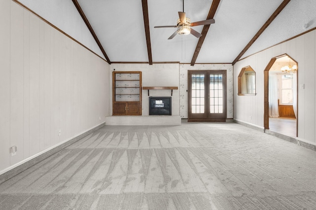 unfurnished living room with arched walkways, lofted ceiling with beams, a brick fireplace, light carpet, and ceiling fan