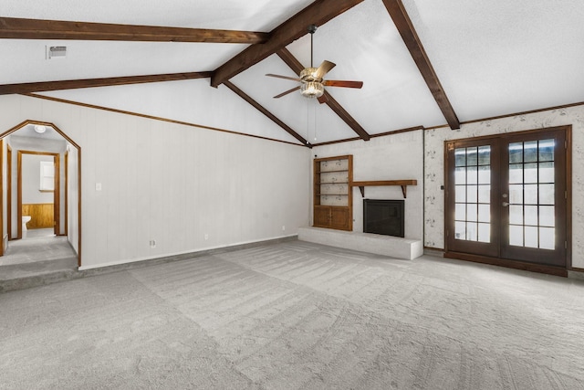 unfurnished living room with lofted ceiling with beams, ceiling fan, a glass covered fireplace, and light colored carpet