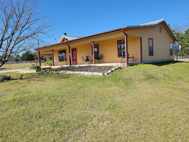 view of front of property with metal roof, a front lawn, and fence