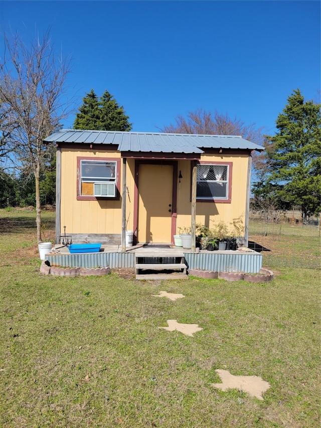 view of front of property with an outbuilding, metal roof, and a front lawn