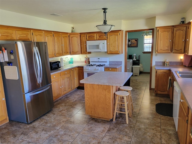 kitchen featuring a center island, pendant lighting, light countertops, brown cabinetry, and white appliances