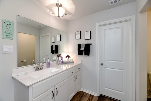 bathroom with visible vents, toilet, vanity, wood finished floors, and baseboards