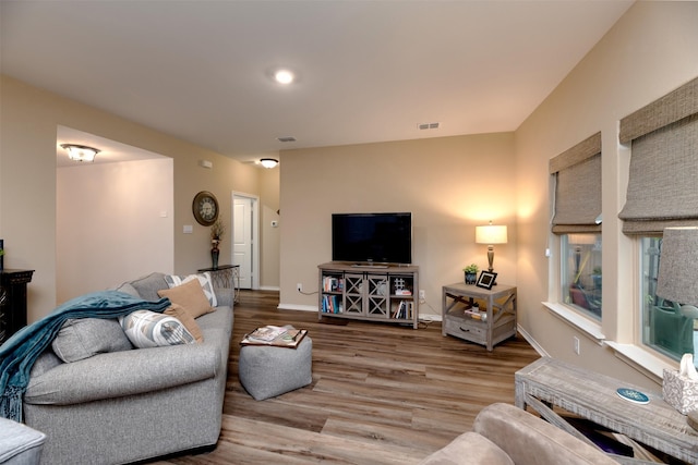 living area with wood finished floors, visible vents, and baseboards