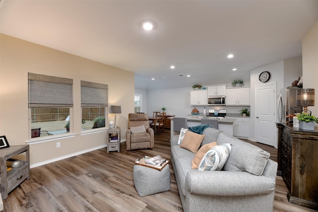 living room with baseboards, recessed lighting, and light wood-style floors