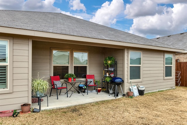 back of property featuring a shingled roof, a lawn, a patio area, and fence