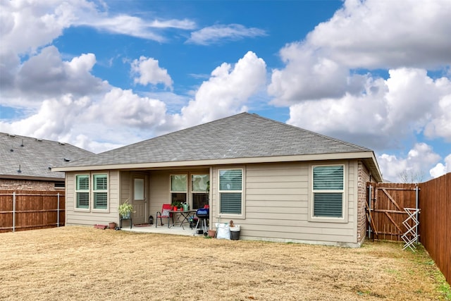 back of house with a fenced backyard, a patio, a lawn, and roof with shingles